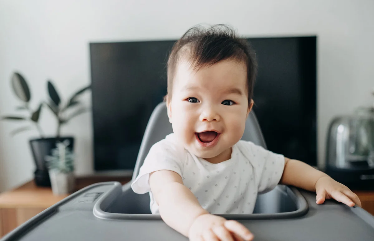 Adorable baby smiling joyfully on high chair