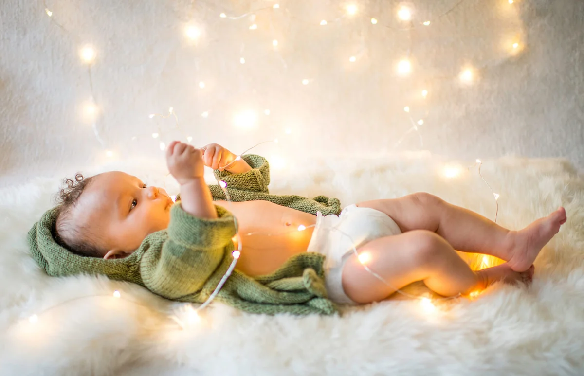 Baby boy lying on furry rug playing with decorative lights