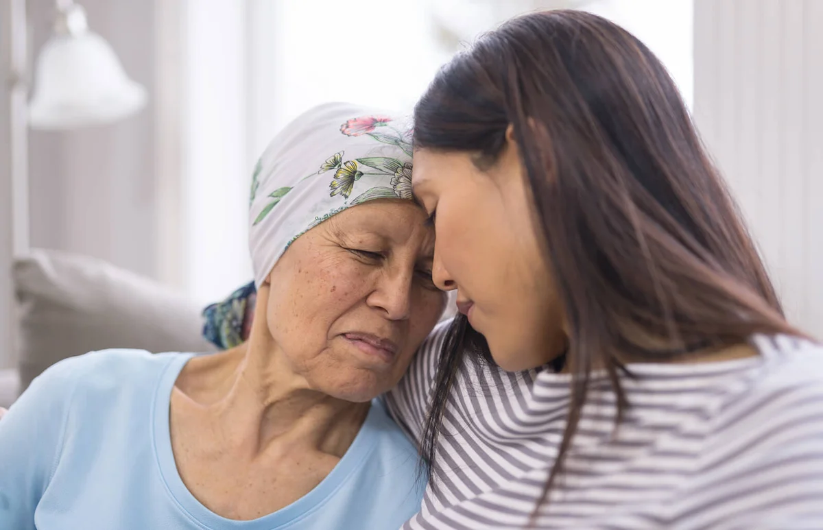 elderly woman with cancer embracing her adult daughter