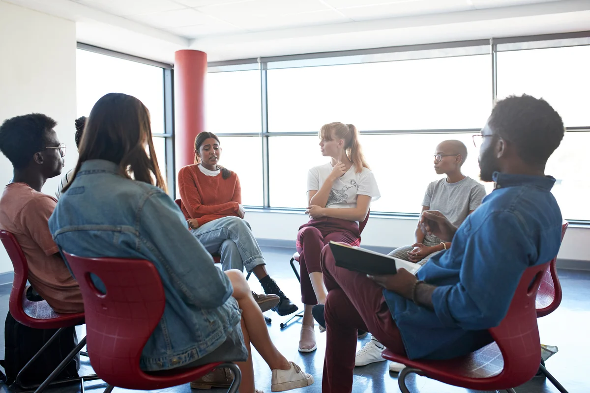 Woman sharing while sitting with mental health instructor in group meeting