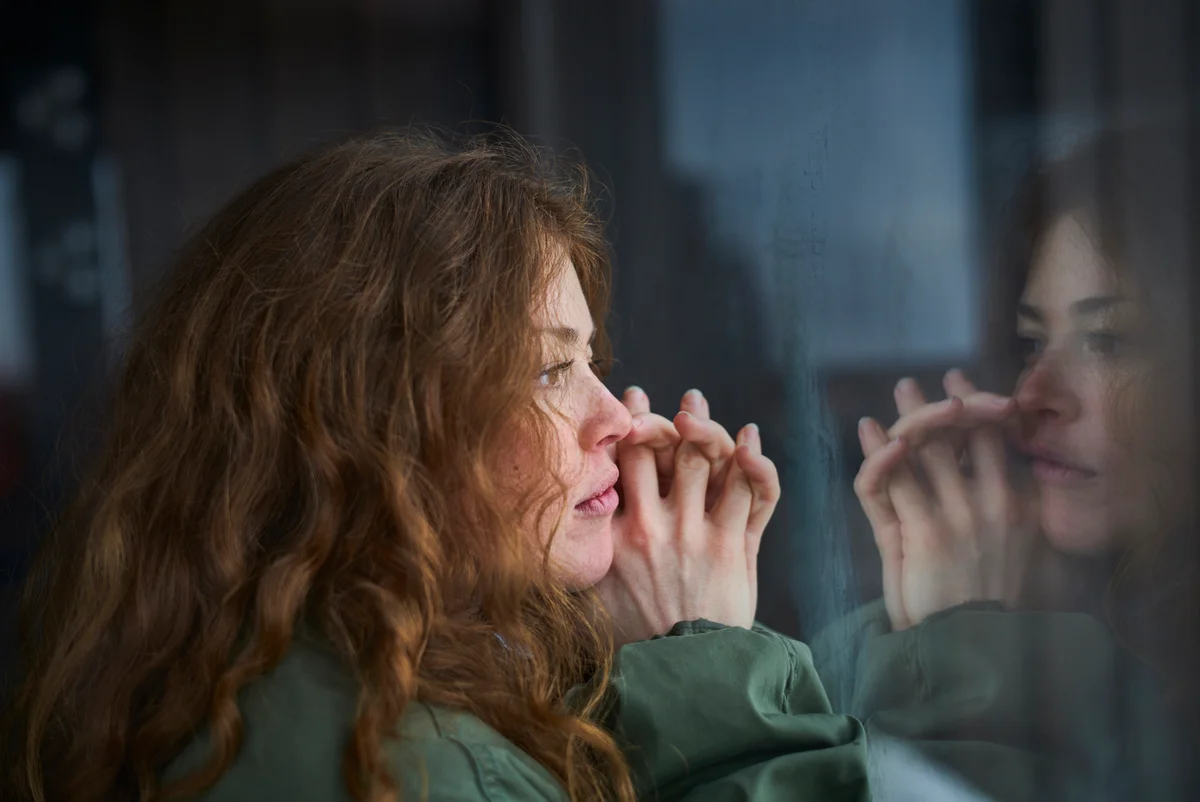 Woman looking out of window into her reflection