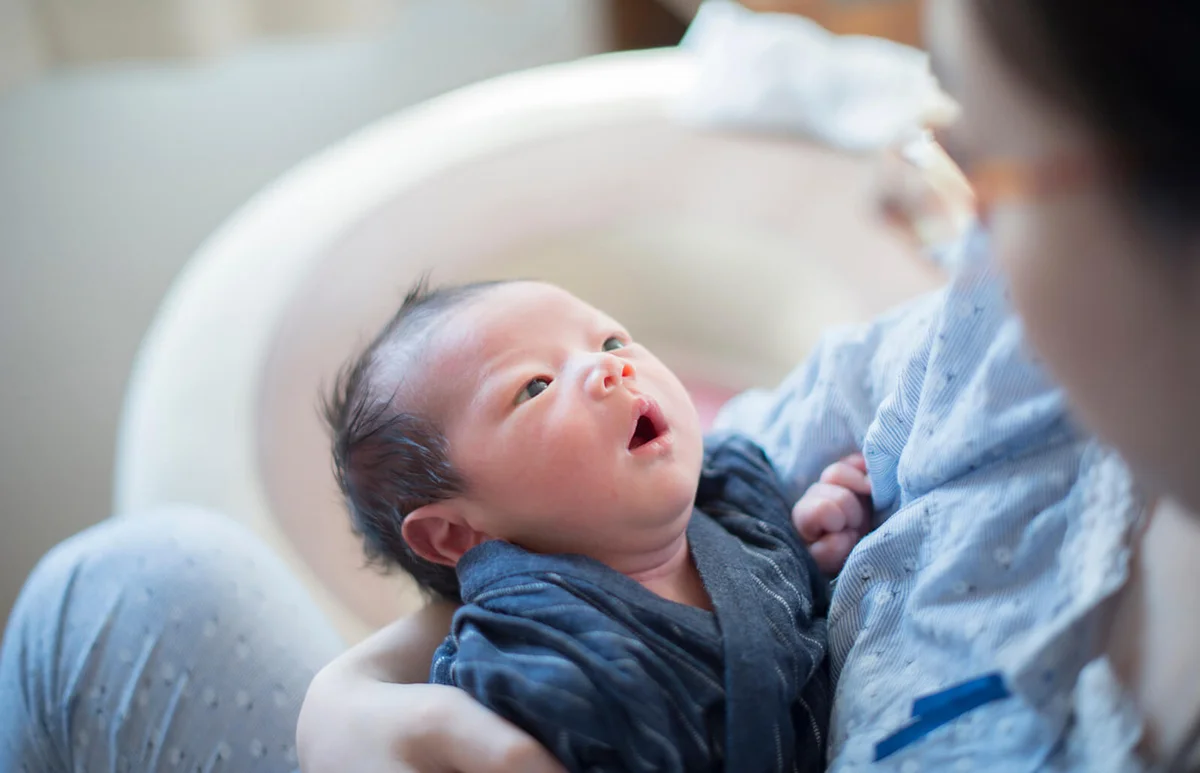 newborn baby looks up his mother