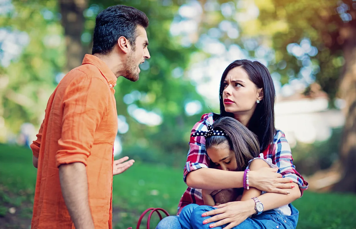 Husband is arguing with wife at the front of their little daughter