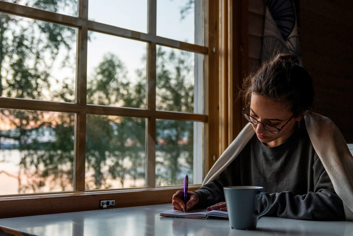 Woman sitting at the window writing into diary