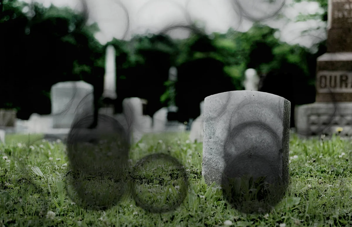 Tombstones On Grassy Field In Cemetery Against Sky