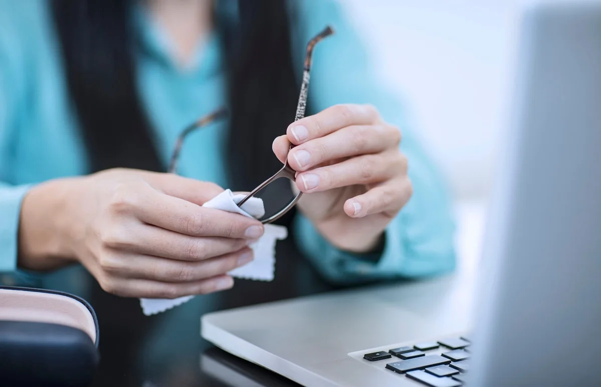 Woman in office cleaning her spectacles