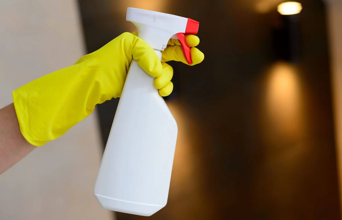 Hand holding white detergent spray bottle