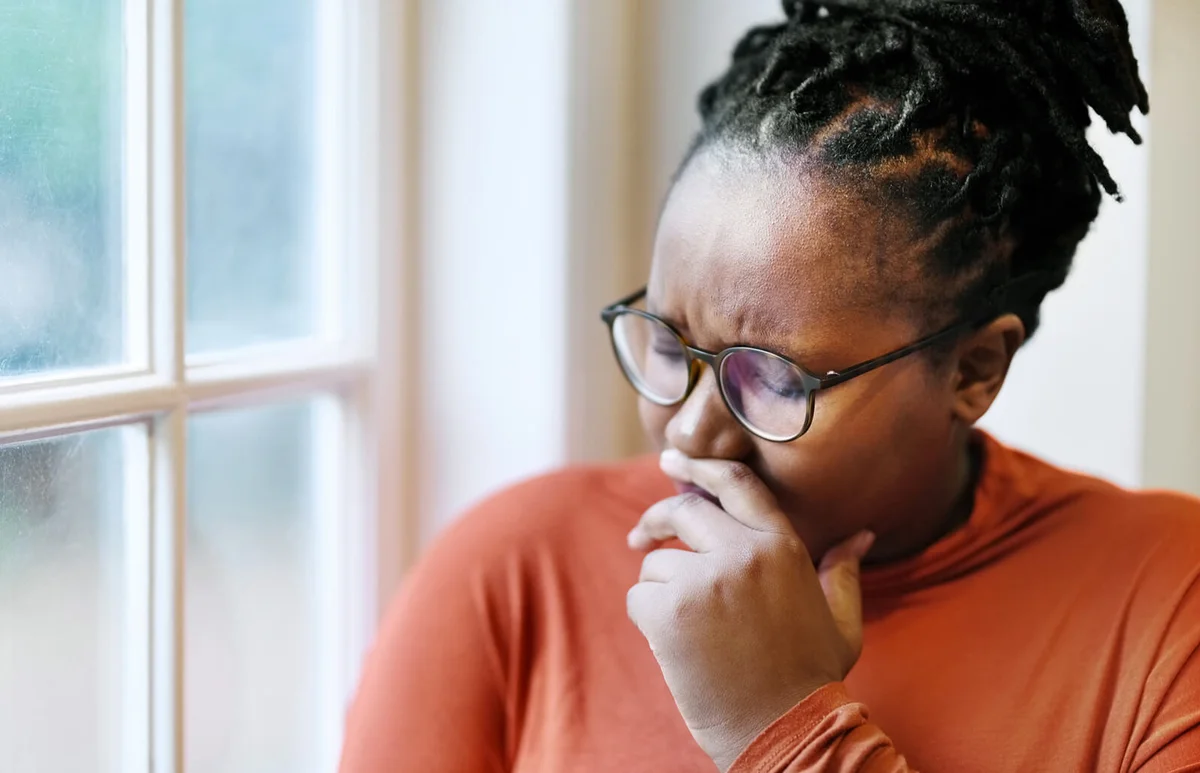 woman crying while sitting by a window at home