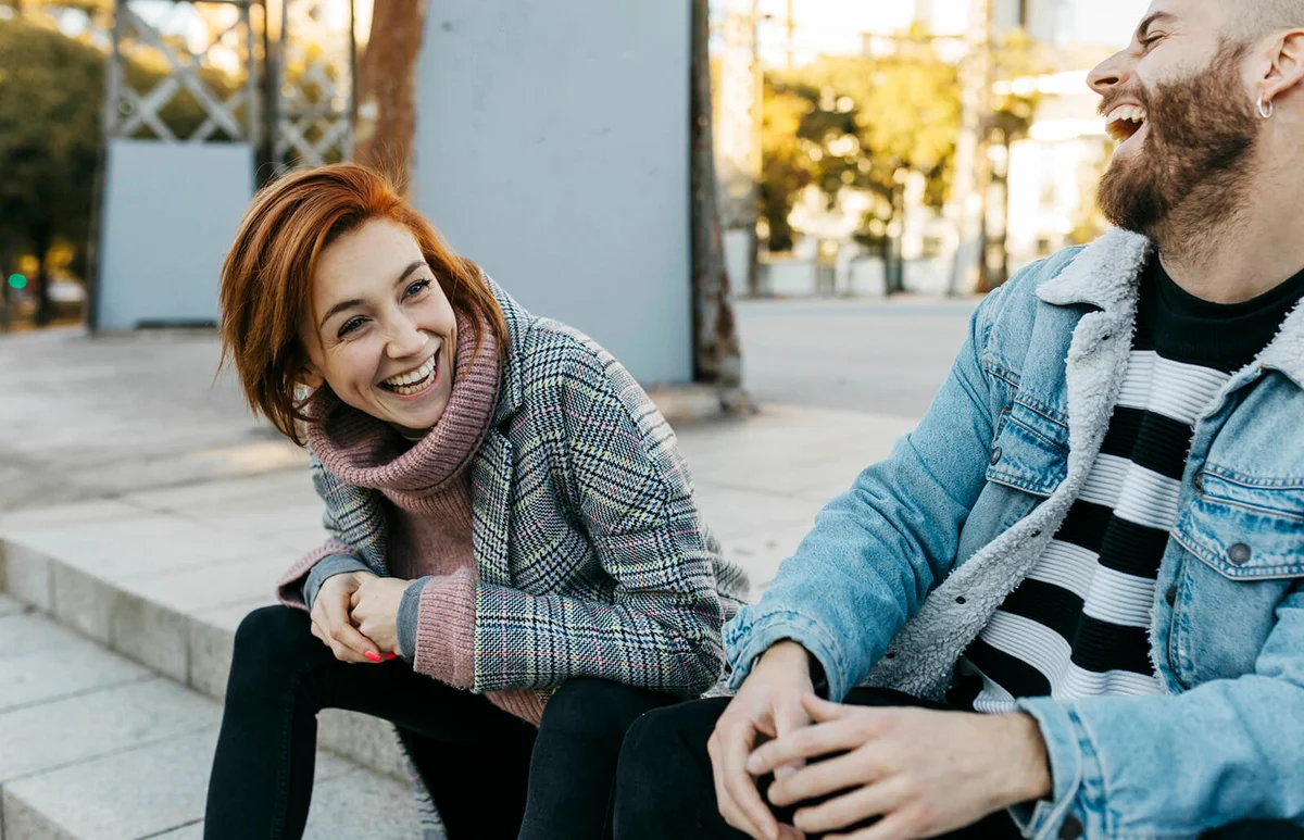 Happy couple sitting outdoors laughing