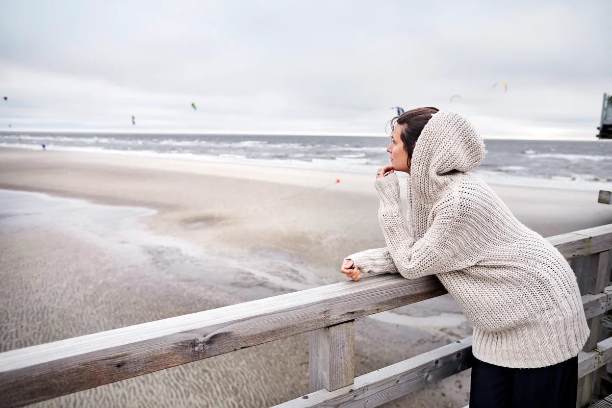 Woman standing on footbridge by the sea