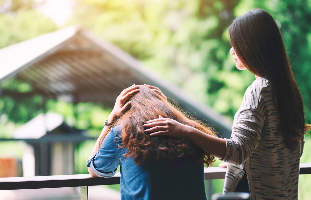 Woman Consoling Sad Friend In Cafe