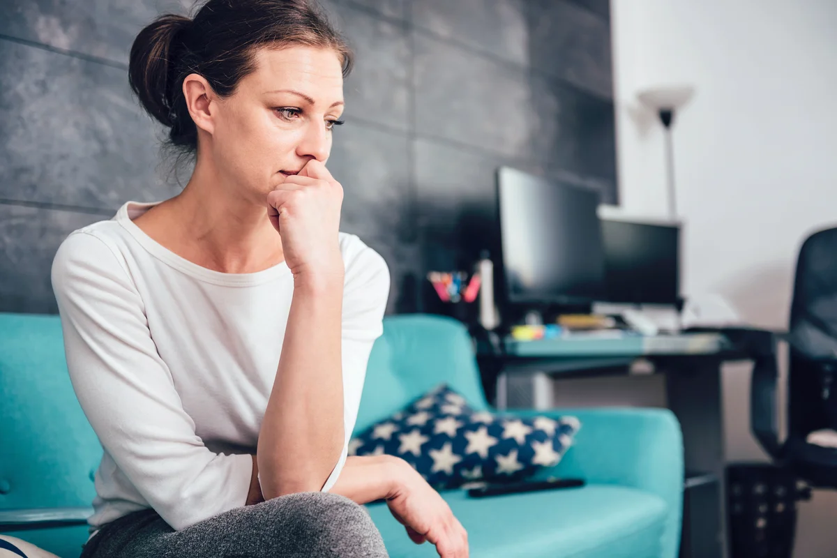 Sad woman sitting on a sofa in the living room