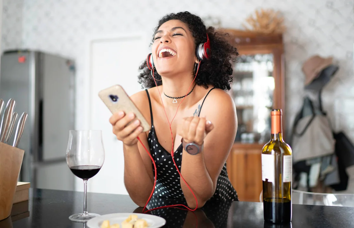 Woman drinking wine while listening her favorite on smart phone
