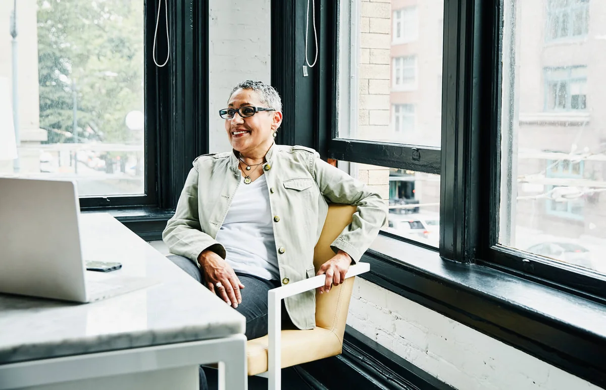 smiling mature female business owner sitting at desk in office