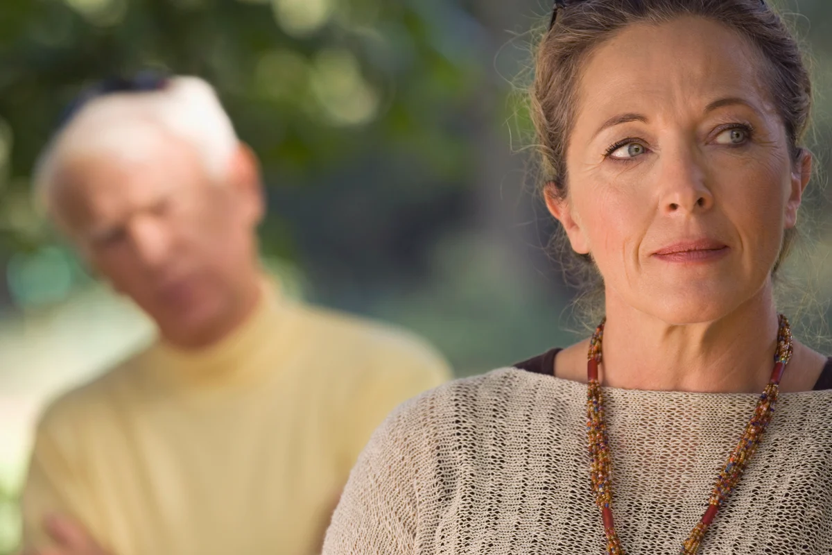 A sad woman, man blurred in the background