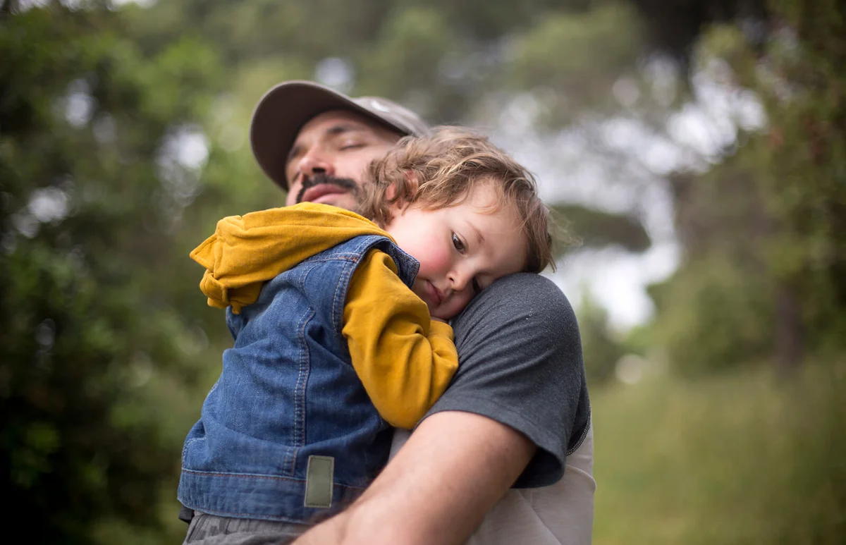 Dad is holding 2 year old boy in the countryside