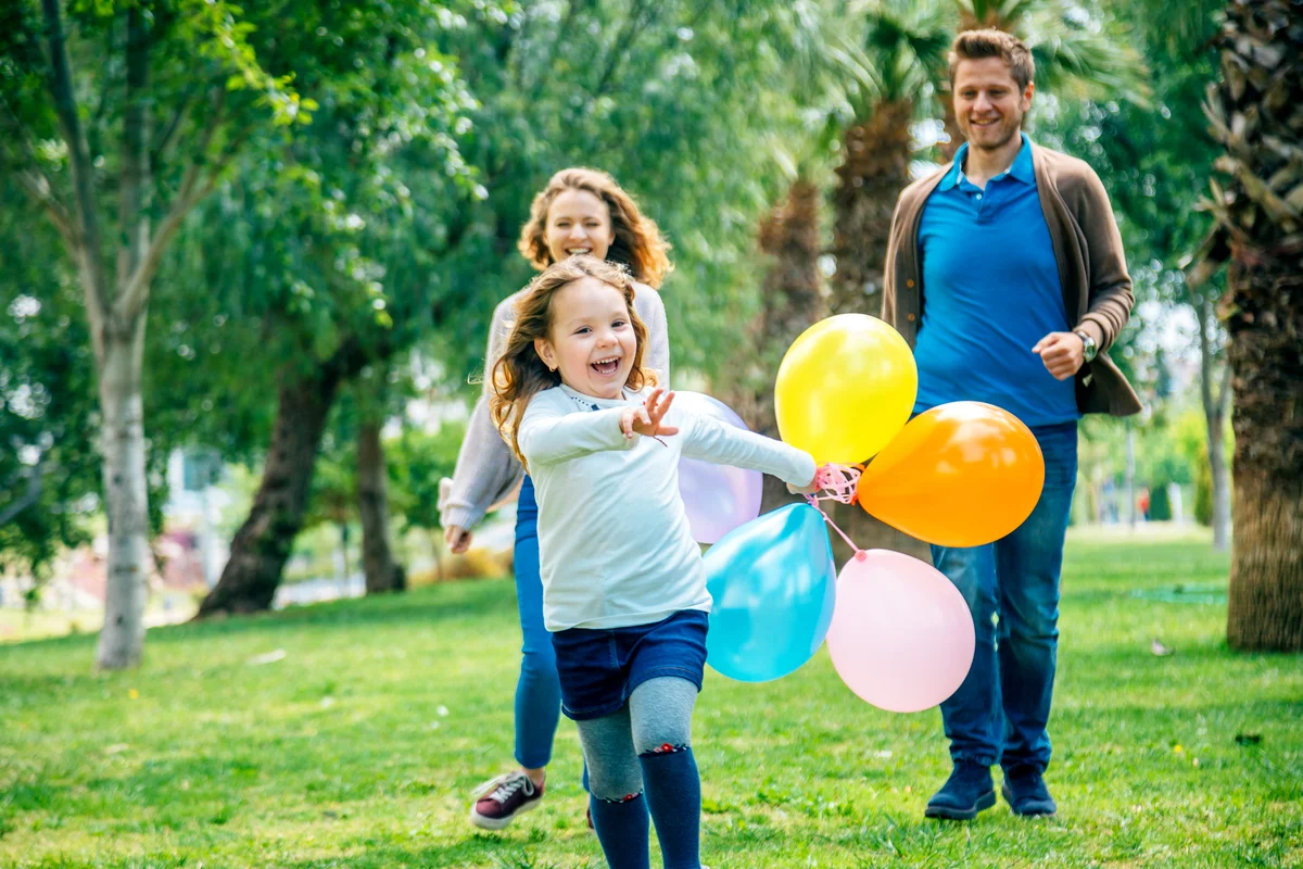 Happy kid girl and her parents having fun outdoors