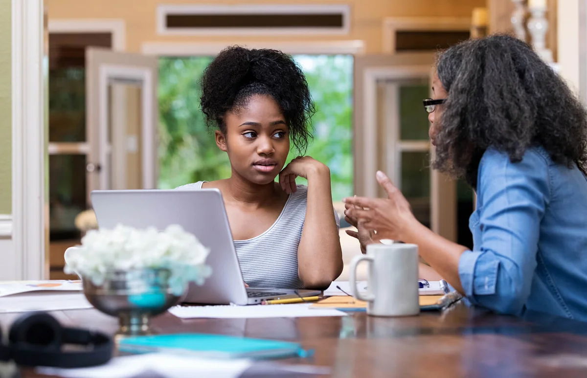mom gestures while helping her daughter study for a college exam