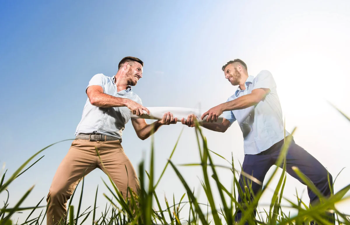 two angry businessmen pulling a paper each to their own side