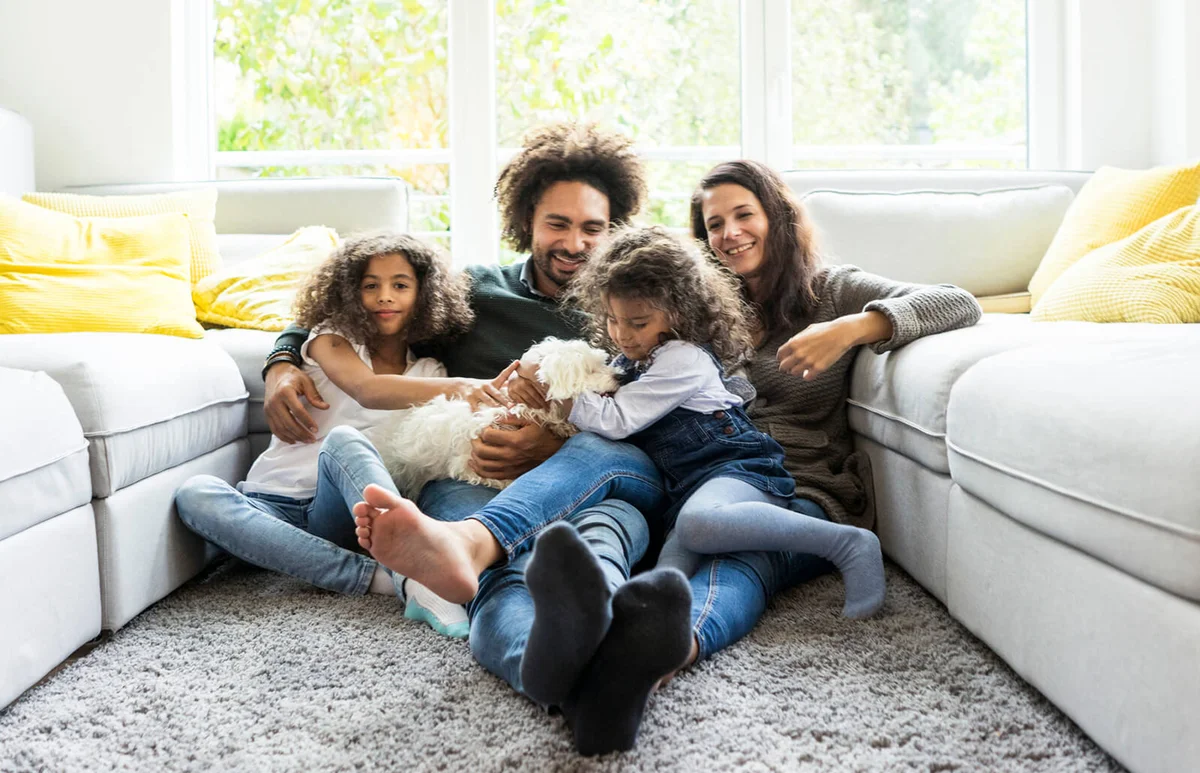 Happy family with dog sitting together in cozy living room