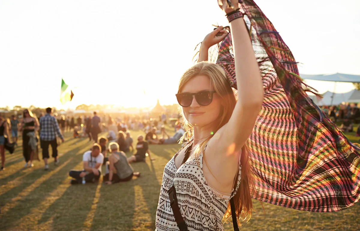 Cute young woman holding up scarf at sunset