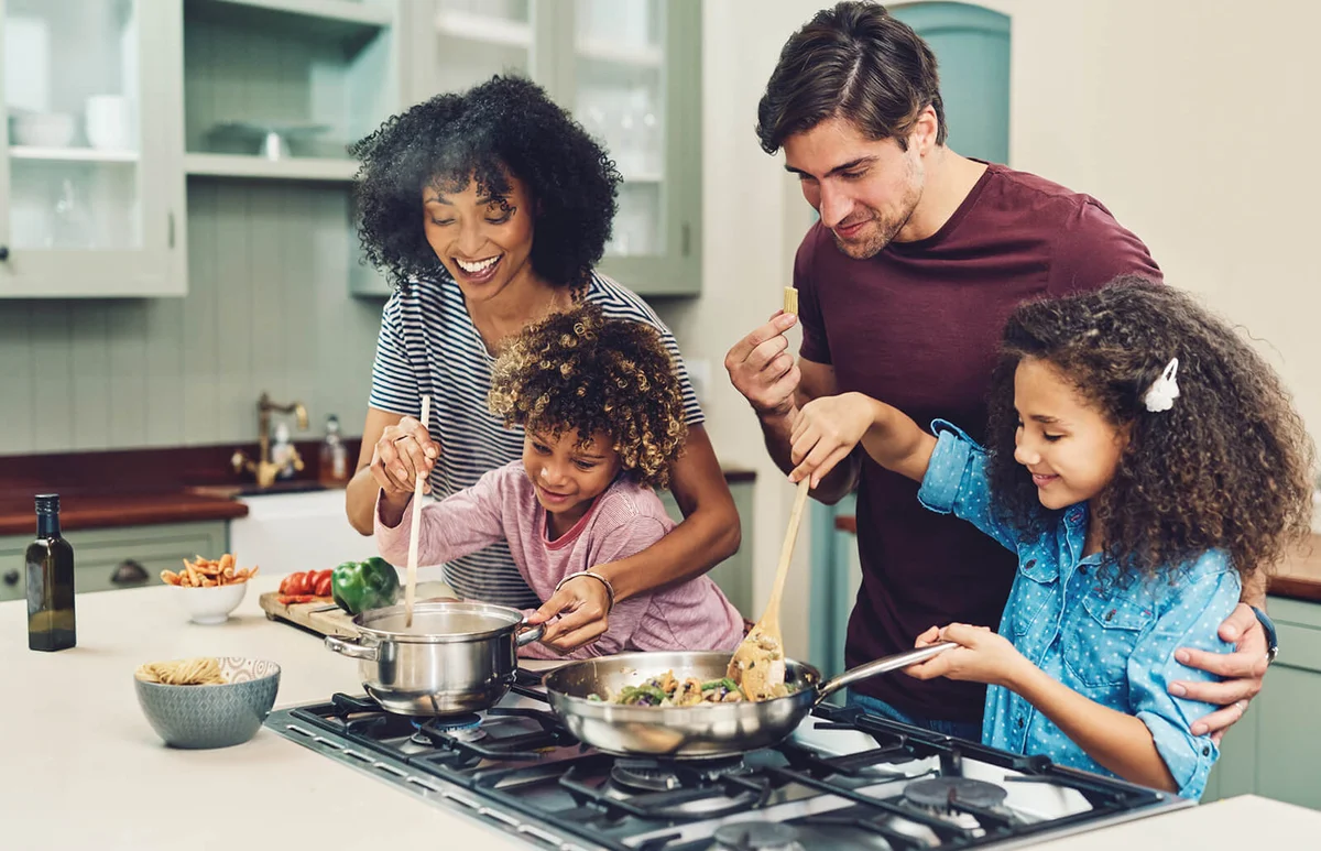family of four cooking together in their kitchen at home