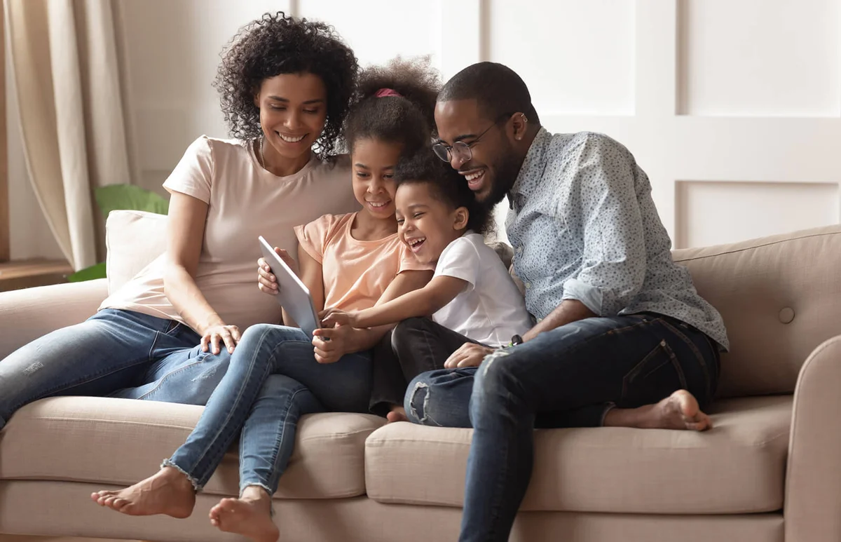 Happy parents and children using digital tablet on sofa