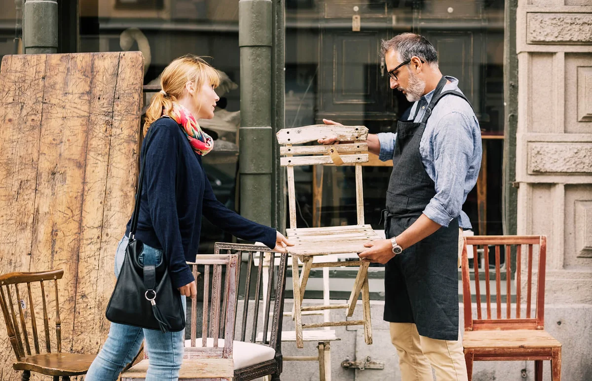 Costumer and owner discussing over chair outside shop