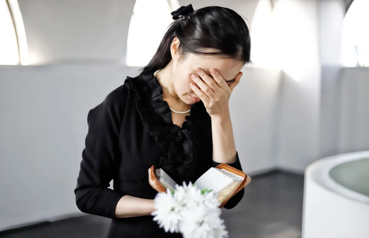 Bereaved holding white flower at funeral