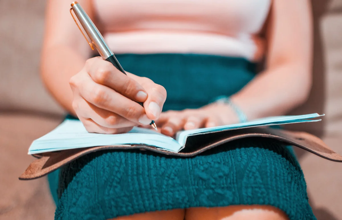 woman is writing on her journal