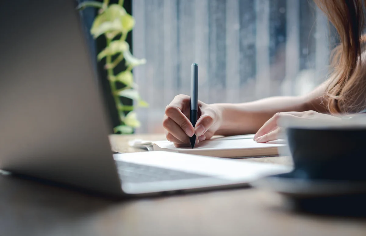 Hand holding pen and writing on paper
