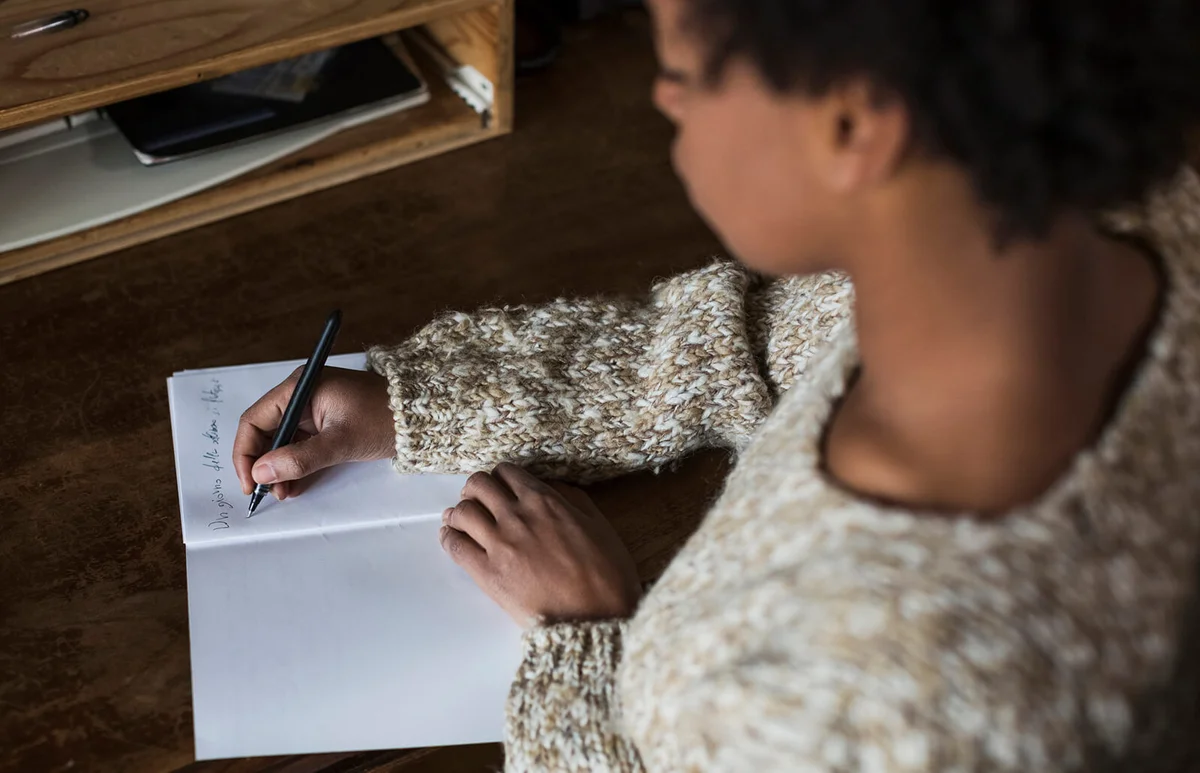 Young woman at desk writing in notebook