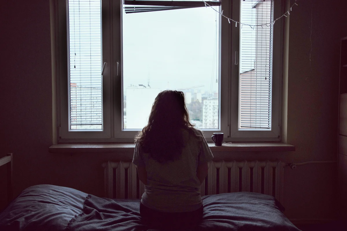 Woman Looking Through Window At Home