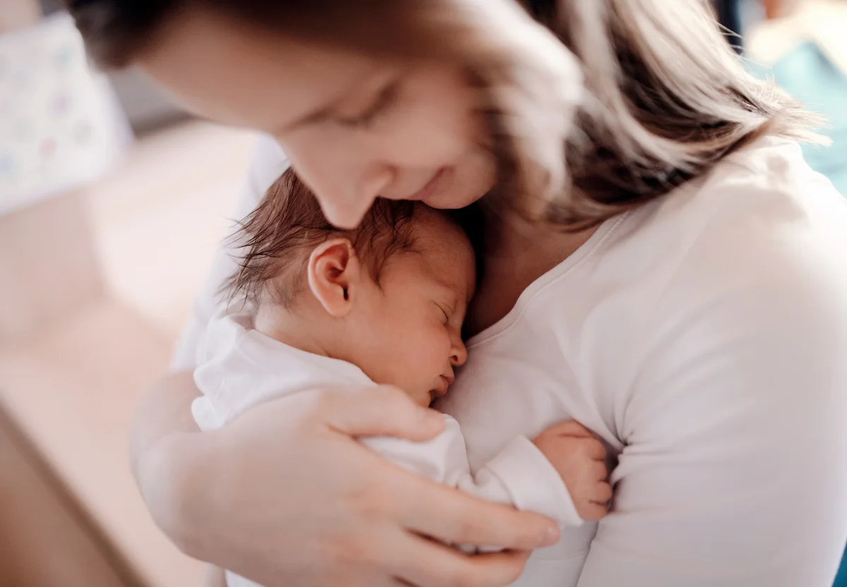 Mother holding a newborn baby son at home