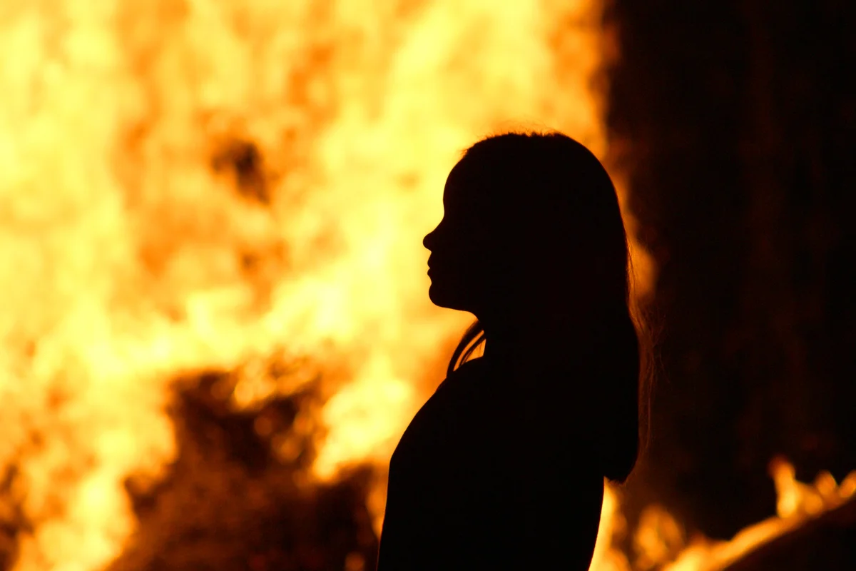 Silhouette of Girl Standing Against Fire At Night