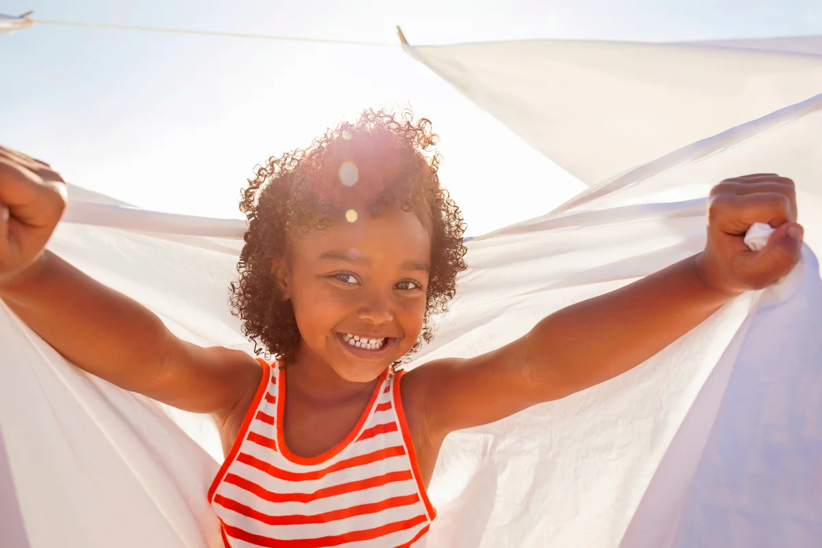 Young girl smiling, holding white sheet