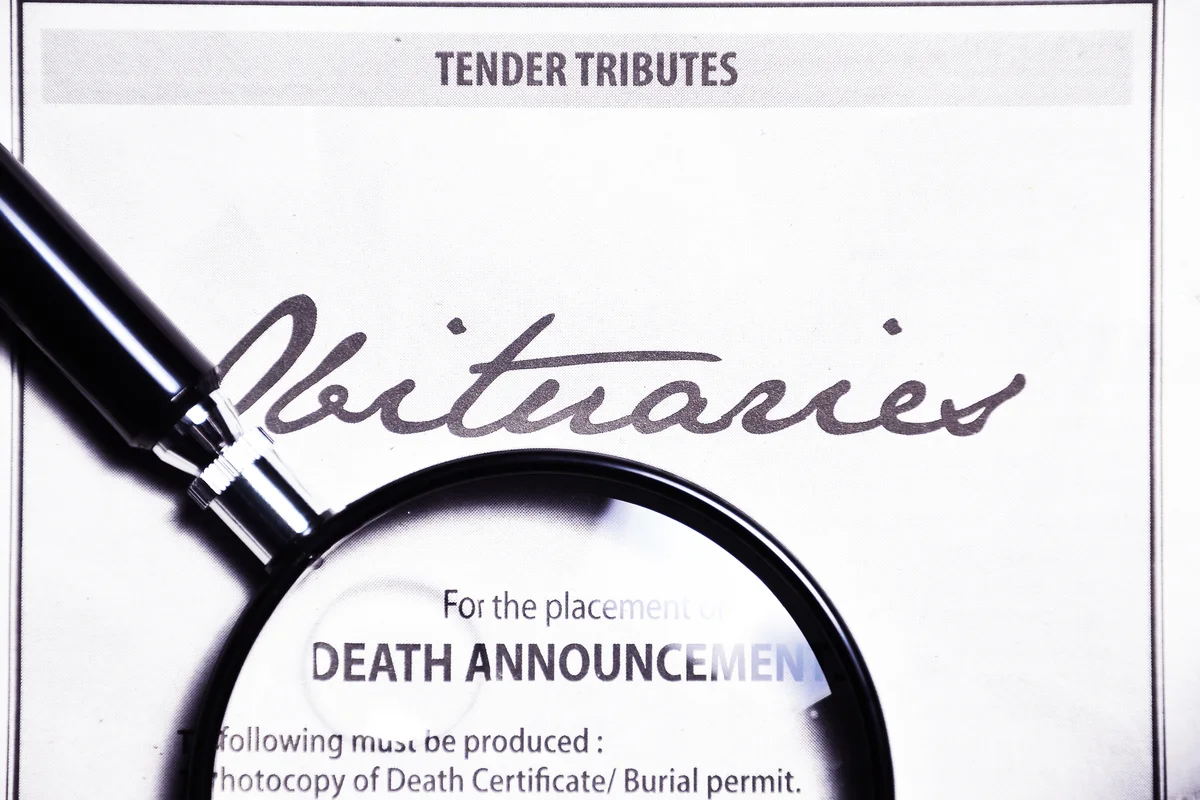 Magnifying glass and obituaries advertisement on newspaper