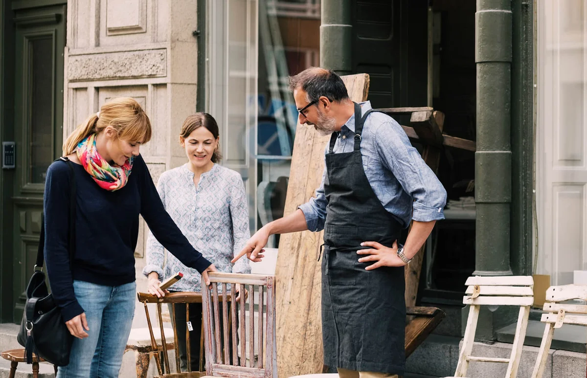 Smiling retailers assisting woman outside shop