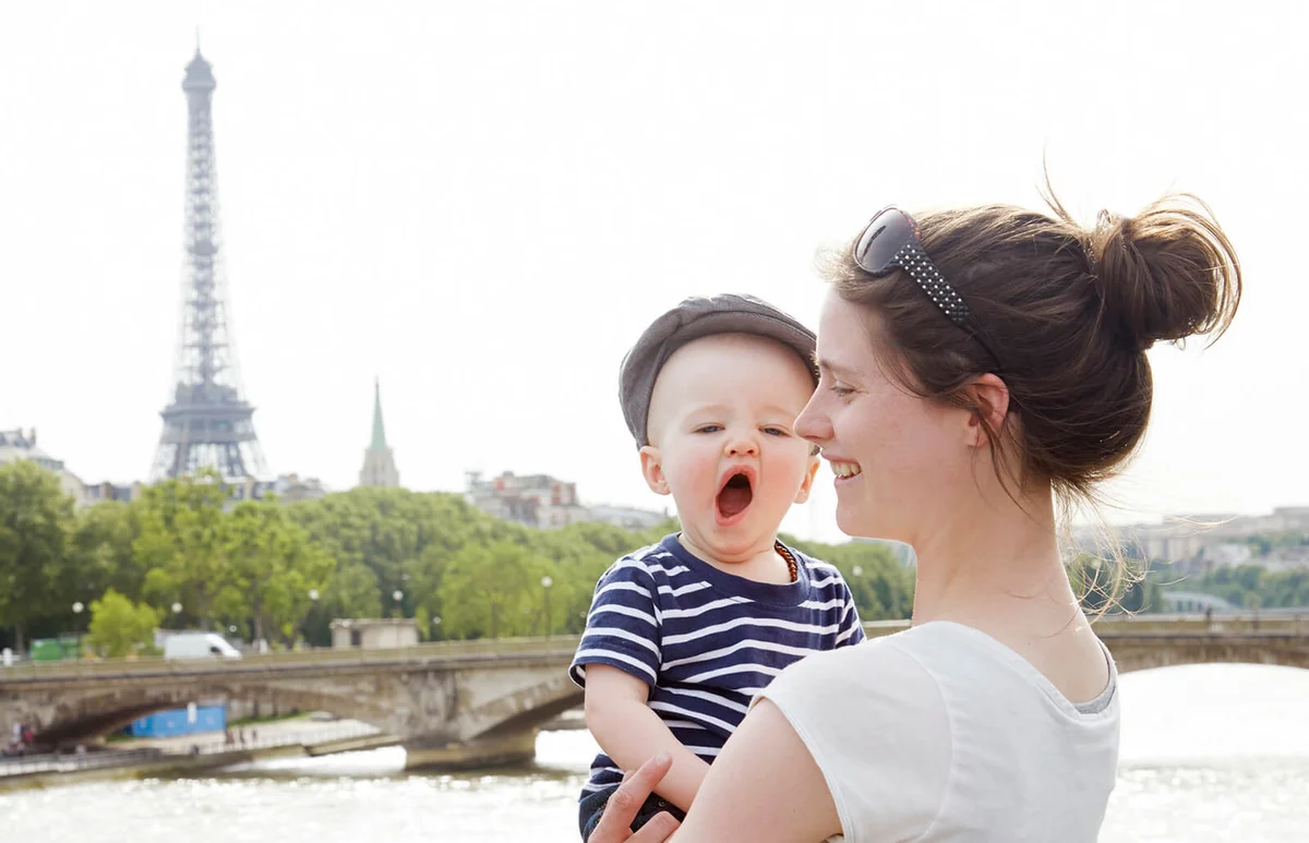 Mom standing with yawning toddler in Paris