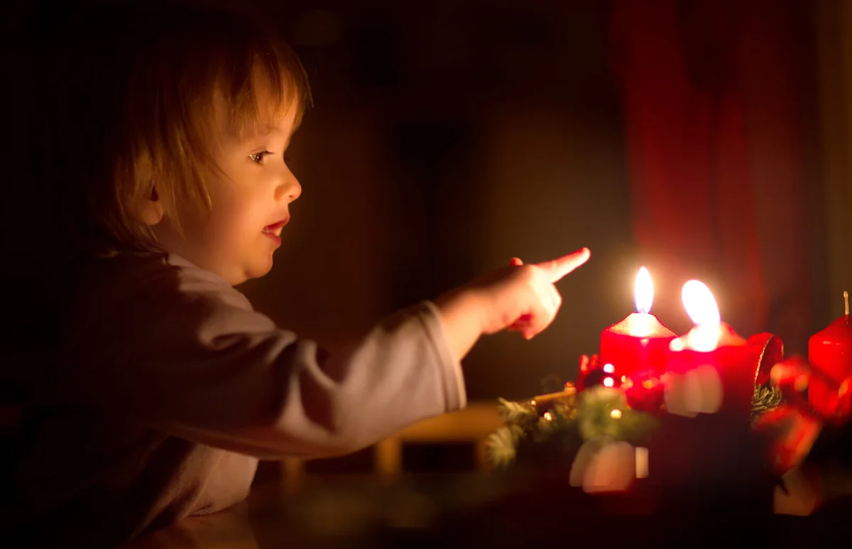 Toddler Boy about to touch burning Advent Candle