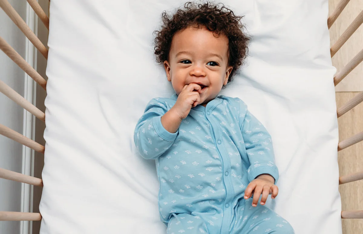 Cute baby boy lying in crib at home