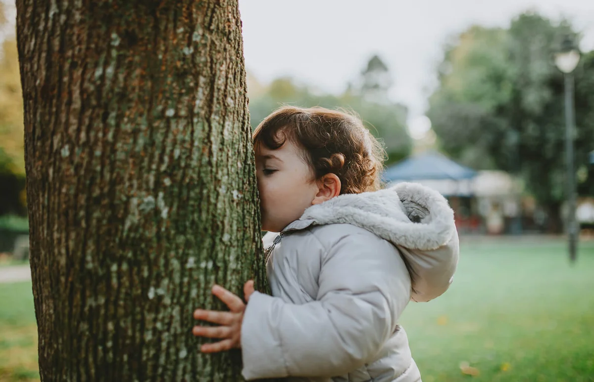 Side view of baby girl kissing tree trunk