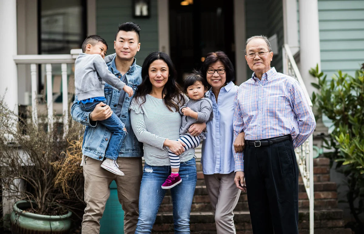 Portrait of 3 generations in front of house