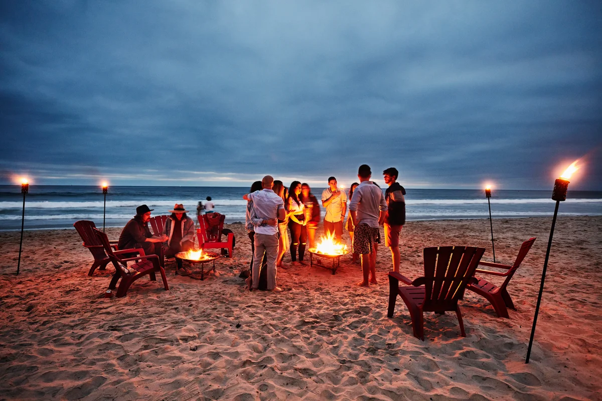Friends gathered around fire on beach