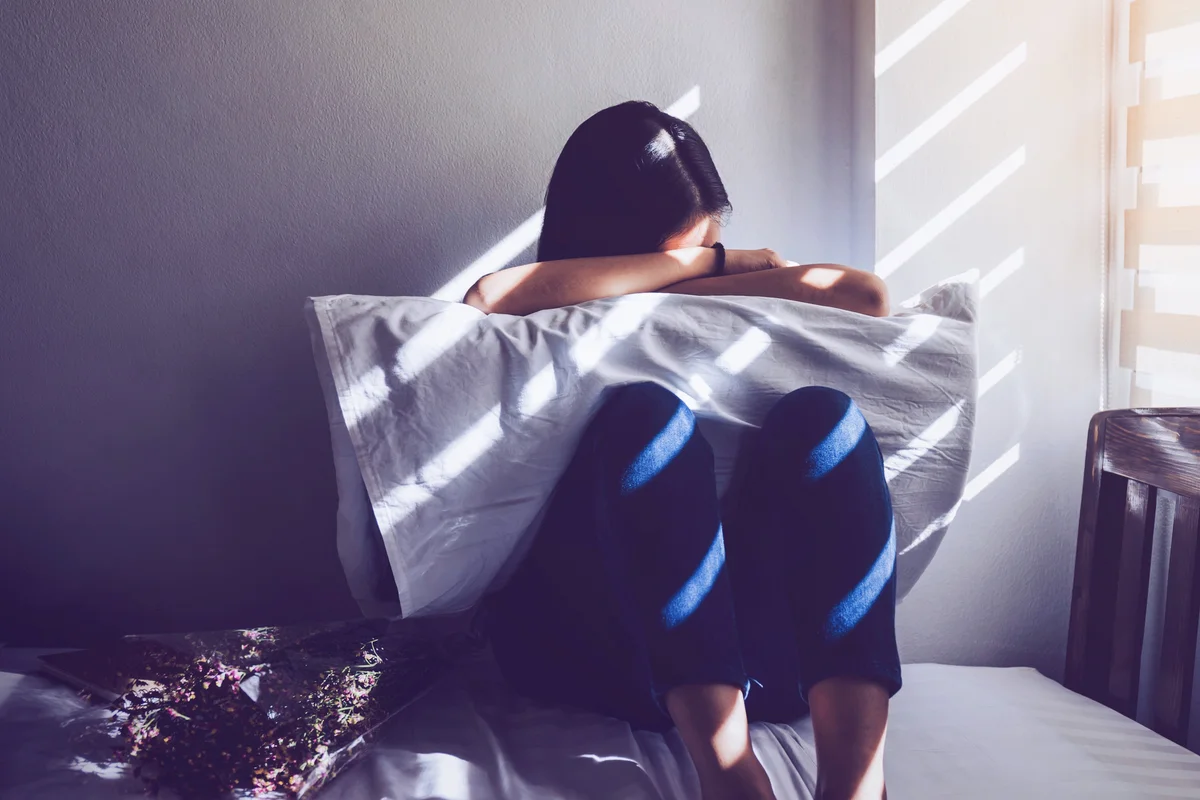 Sad Woman Sitting On Bed At Home