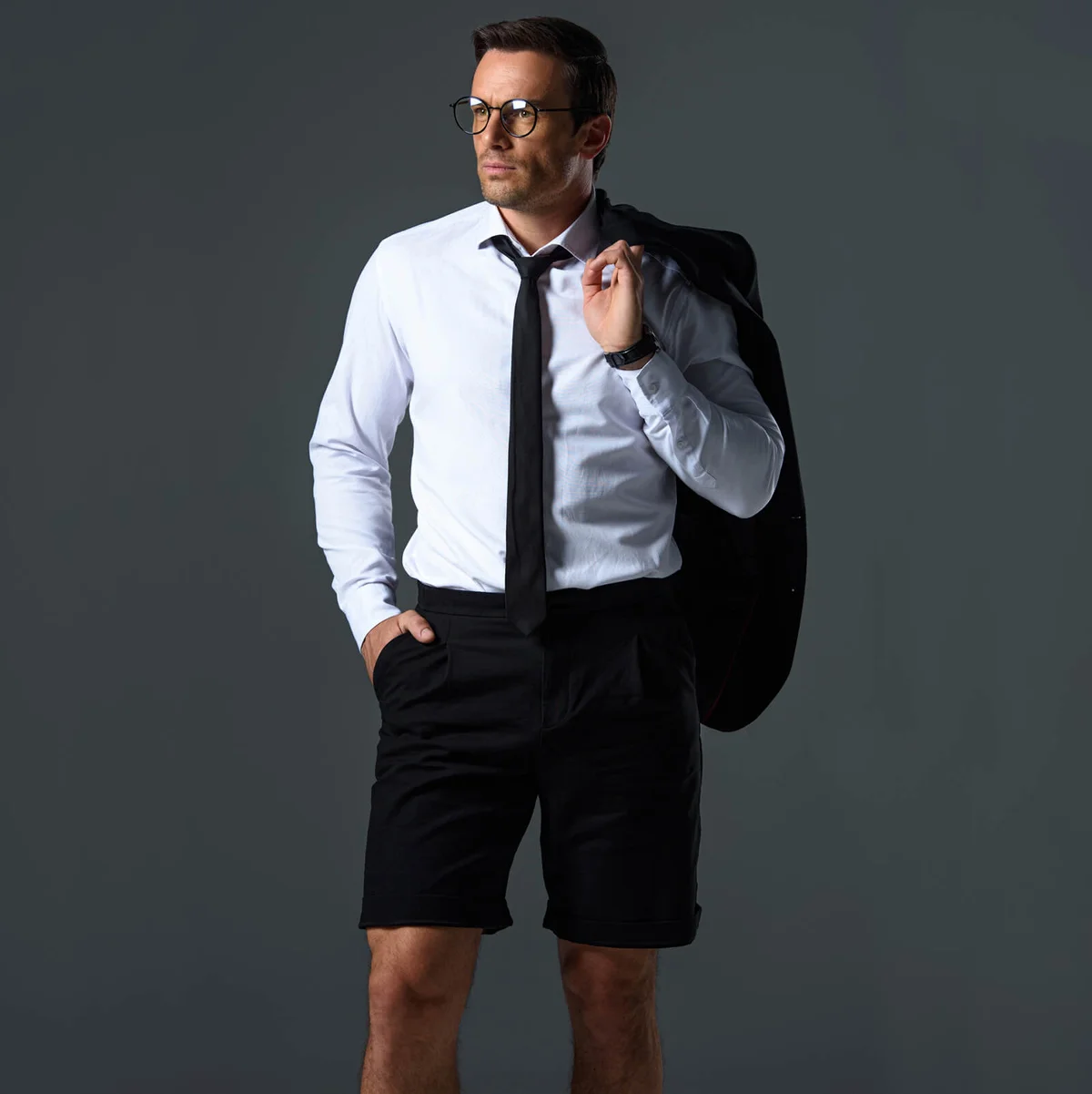 confident stylish man with eyeglasses in shorts holding jacket on shoulder