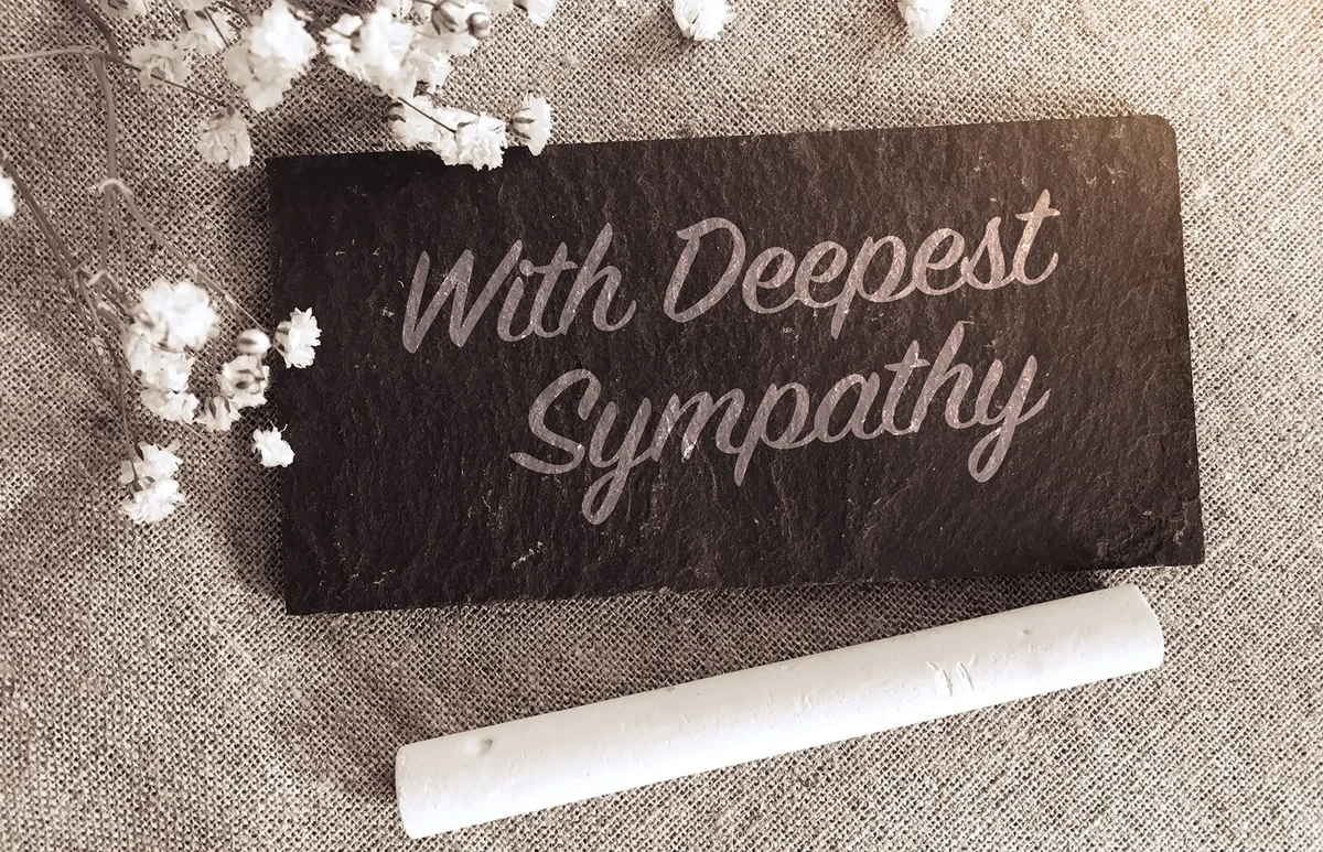 "With deepest sympathy" note with flowers on small chalk board