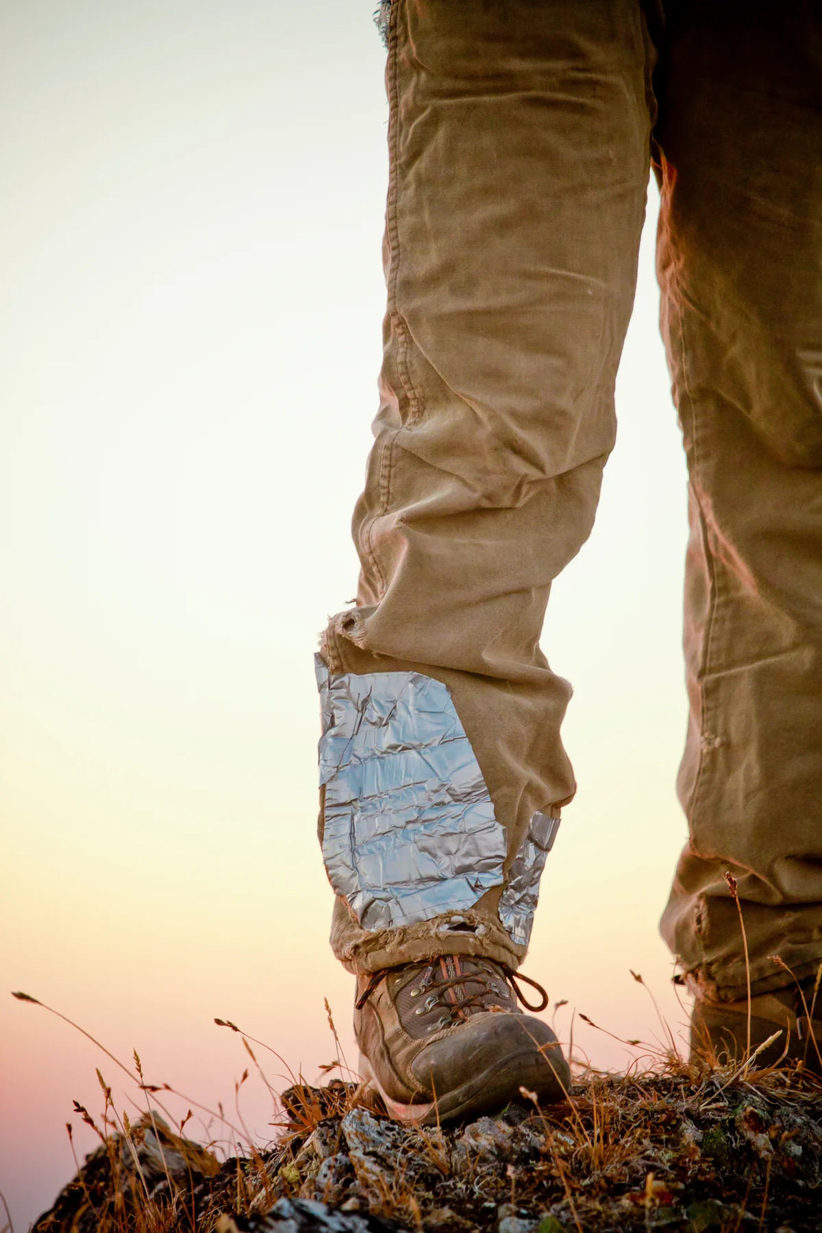 A hikers tattered pant leg fixed with duct tape