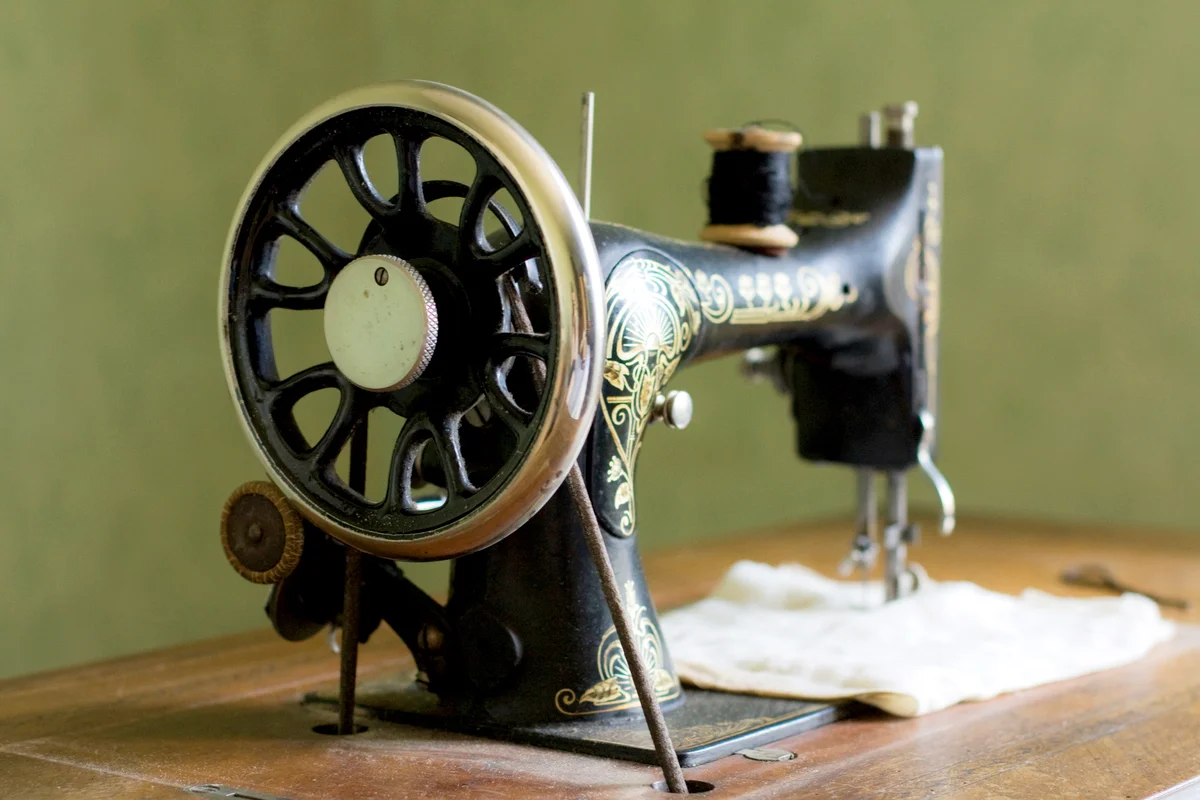 Vintage black and golden sewing machine with well and wooden table