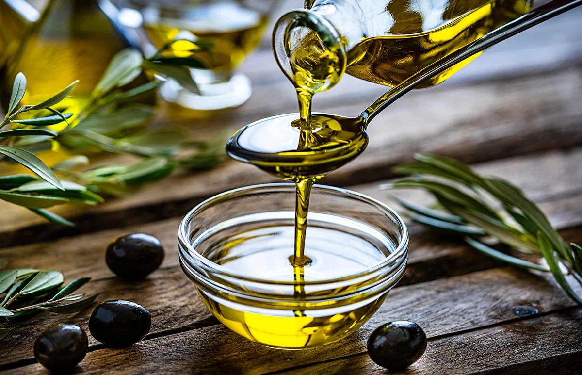 Pouring extra virgin olive oil in a glass bowl
